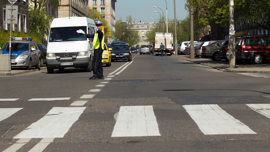 Sytuacja drogowa do pytania: Czy sygnał, który daje policjant, zezwala na wjazd na skrzyżowanie?