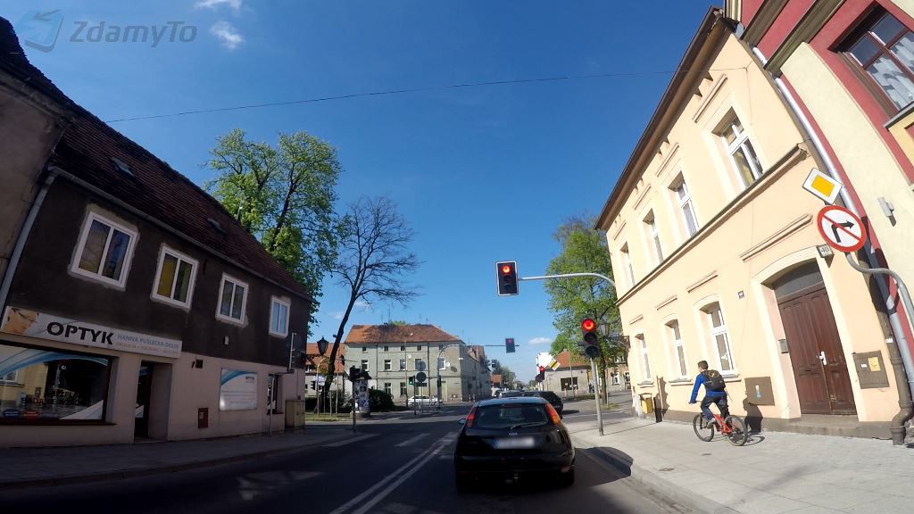 Sytuacja drogowa do pytania: Jaki odstęp od poprzedzającego pojazdu musisz utrzymać stojąc przed skrzyżowaniem i czekając na sygnał zielony?