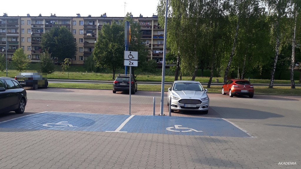 Sytuacja drogowa do pytania: Czy dozwolony jest postój na wyznaczonych miejscach dla osób niepełnosprawnych, jeśli nie będzie trwał więcej niż 15 minut?