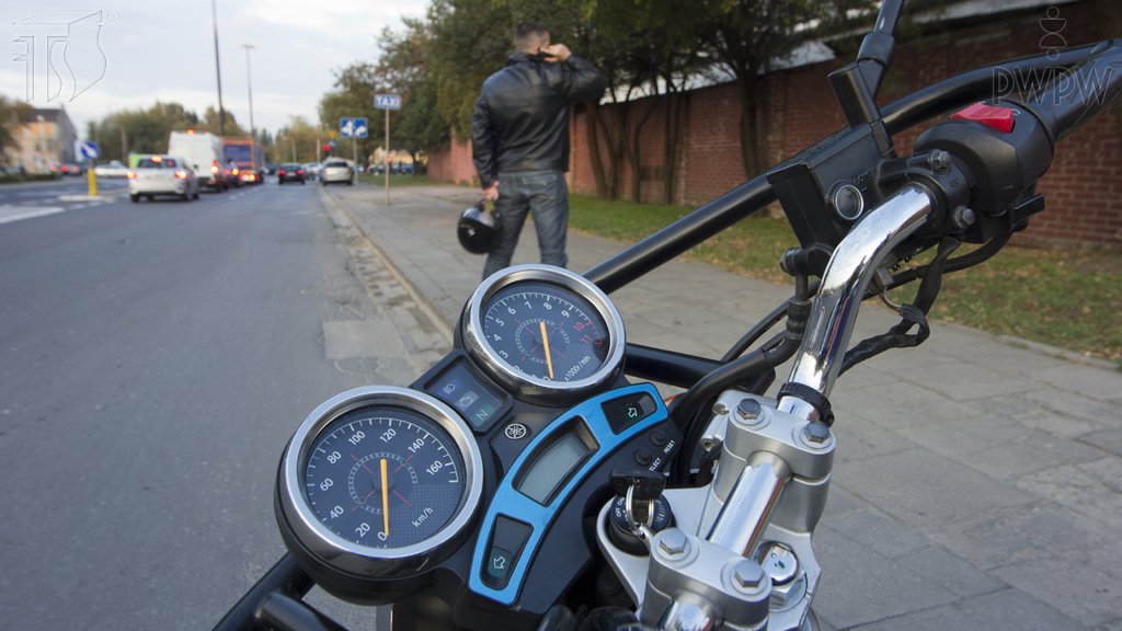 Sytuacja drogowa do pytania: Czy tak pozostawiony na postoju bez opieki motocykl jest prawidłowo zabezpieczony przed możliwością uruchomienia go przez osobę niepowołaną?